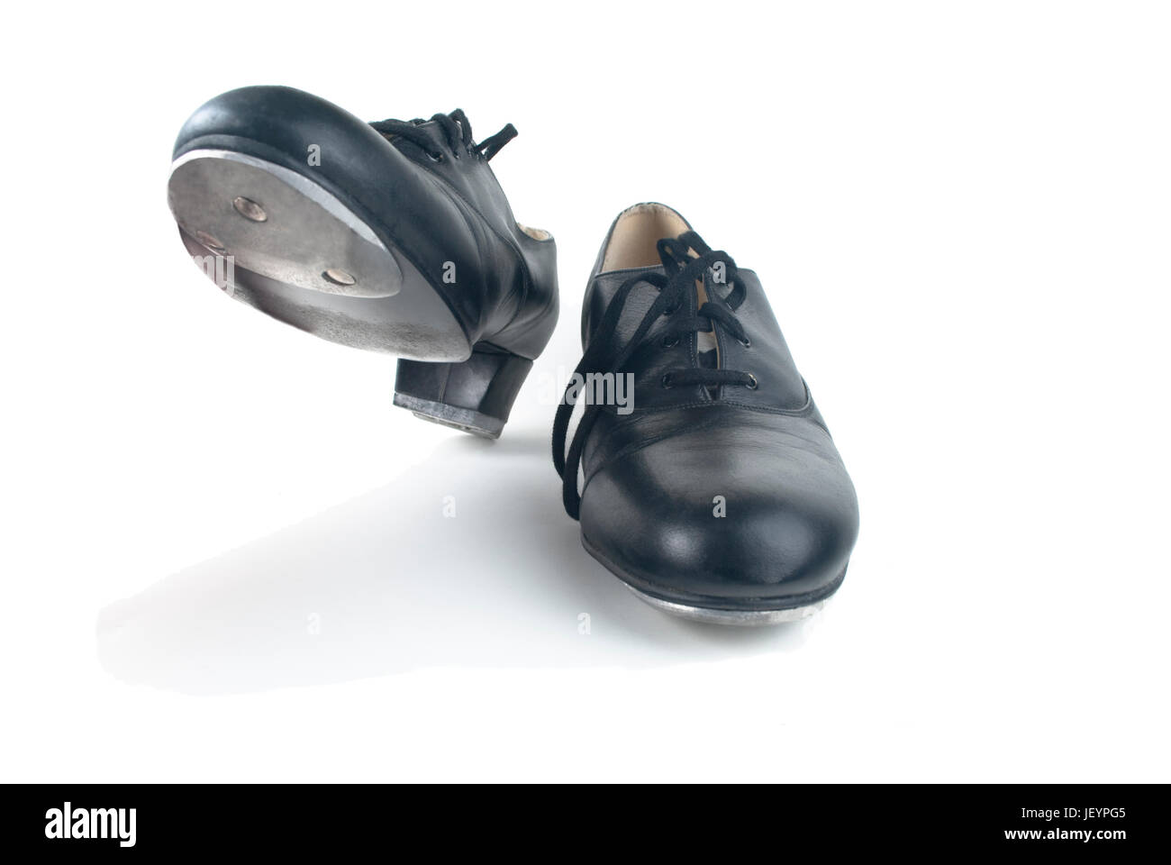 Une paire de chaussures de robinet noir avec des lacets, un sur le sol et l'un, prêt à l'étape. Fond blanc, les ombres visibles. Banque D'Images