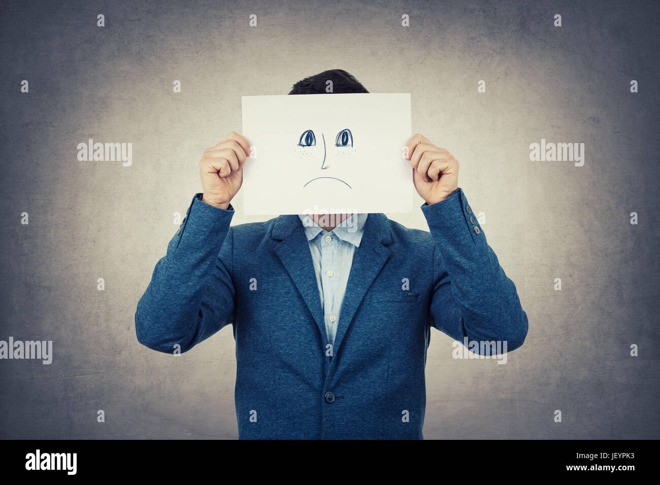 Businessman couvrant son visage à l'aide d'un papier blanc avec appelée triste émoticône croquis, comme un faux masque pour cacher son émotion réelle de la société. Isolé Banque D'Images