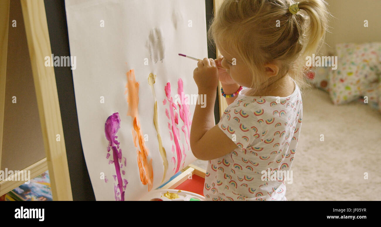 Petite fille, je suis debout à un chevalet de peinture Banque D'Images