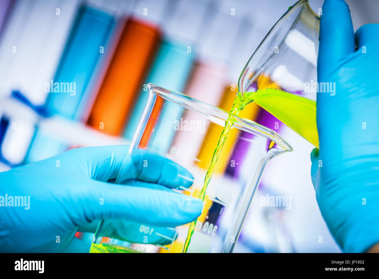 Scientist mélange deux substances colorées dans un laboratoire. Verser liqiud à un flacon. La science de la chimie et de l'équipement. Banque D'Images