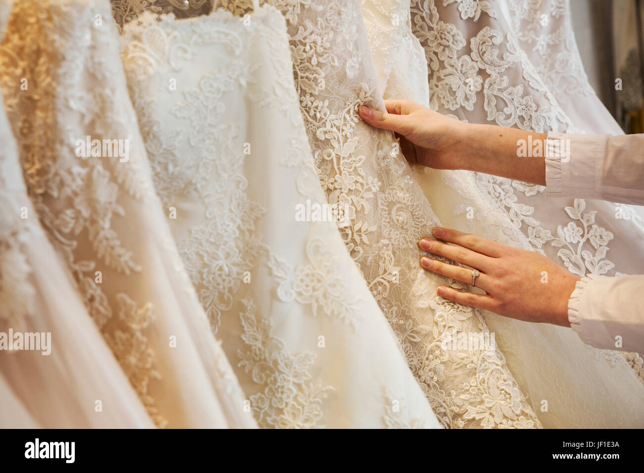 Lignes de robes de sur l'affichage dans une boutique de robe de mariage spécialisés. Close up de jupes, certains avec une dentelle, dans une variété de teintes de couleur Banque D'Images