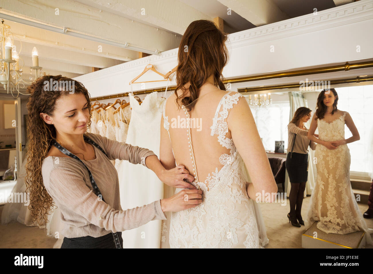 Une couturière en tenant dans une robe de mariage, et le raccord au client,  une jeune femme. La sélection d'une mariée sa robe dans une boutique  spécialisée Photo Stock - Alamy