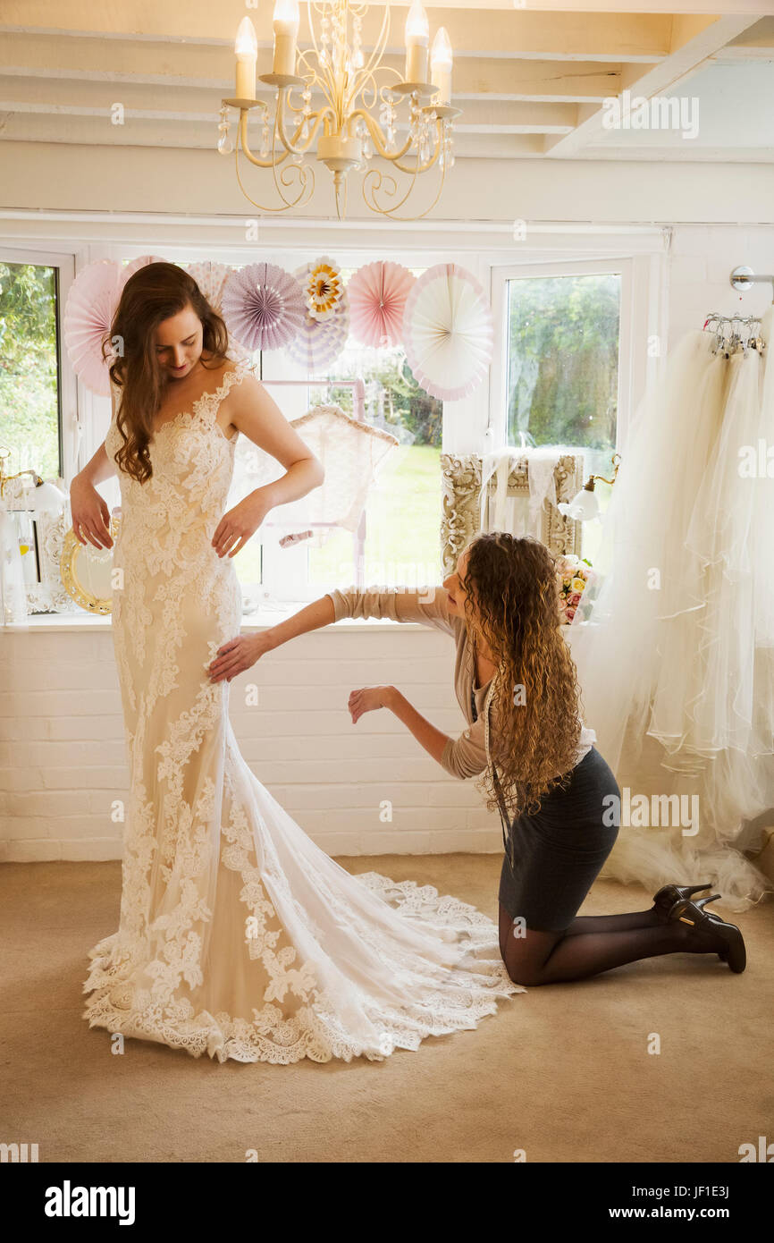 Une couturière en tenant dans une robe de mariage, et le raccord au client,  une jeune femme. La sélection d'une mariée sa robe dans une boutique  spécialisée Photo Stock - Alamy