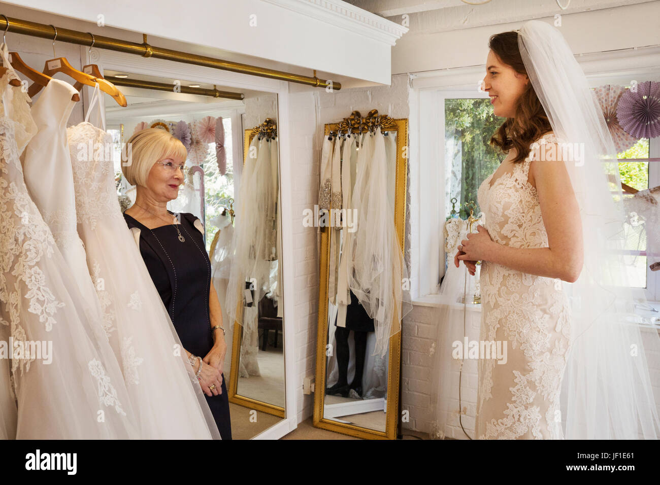 Une femme, une épouse d'être, d'essayer sur des robes avec l'aide d'un  vendeur, dans une robe de mariage boutique Photo Stock - Alamy