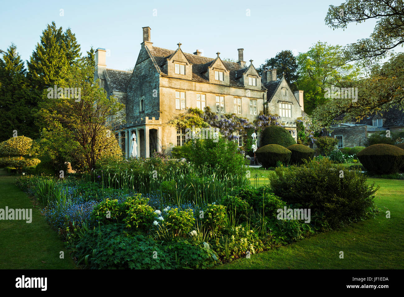 Vue extérieure d'une maison de campagne du xviie siècle à partir d'un jardin avec fleurs, arbustes et arbres. Banque D'Images