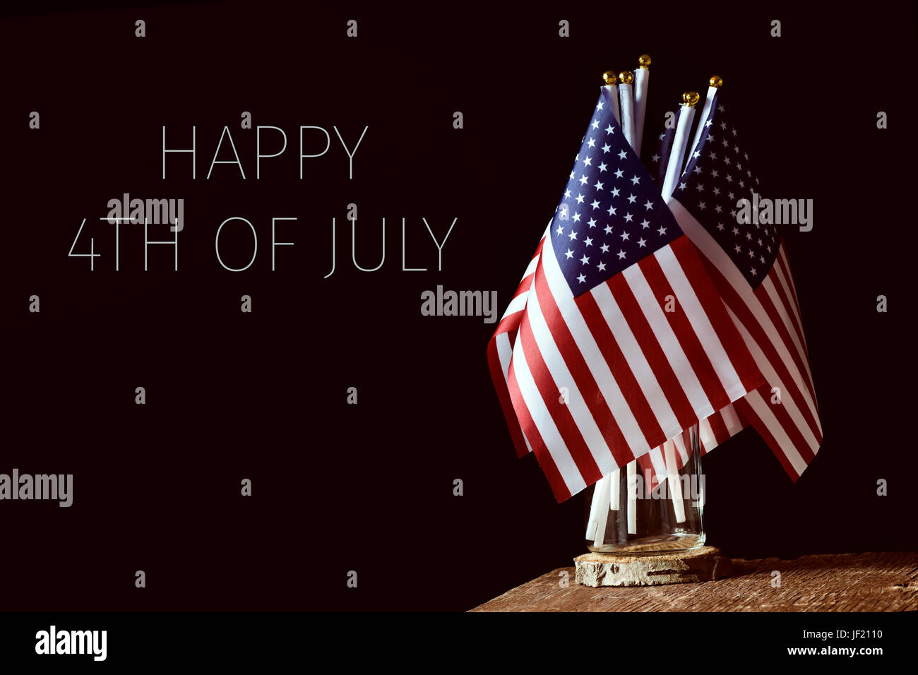 Certains des drapeaux américains dans un bocal en verre, sur une surface en bois rustique et le texte heureux 4 juillet sur fond noir Banque D'Images
