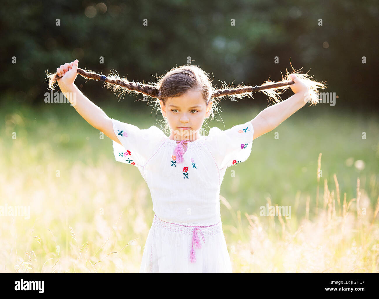 Petite fille heureuse avec les tresses serrées portant blouse roumaine traditionnelle fonctionne en dehors de Banque D'Images