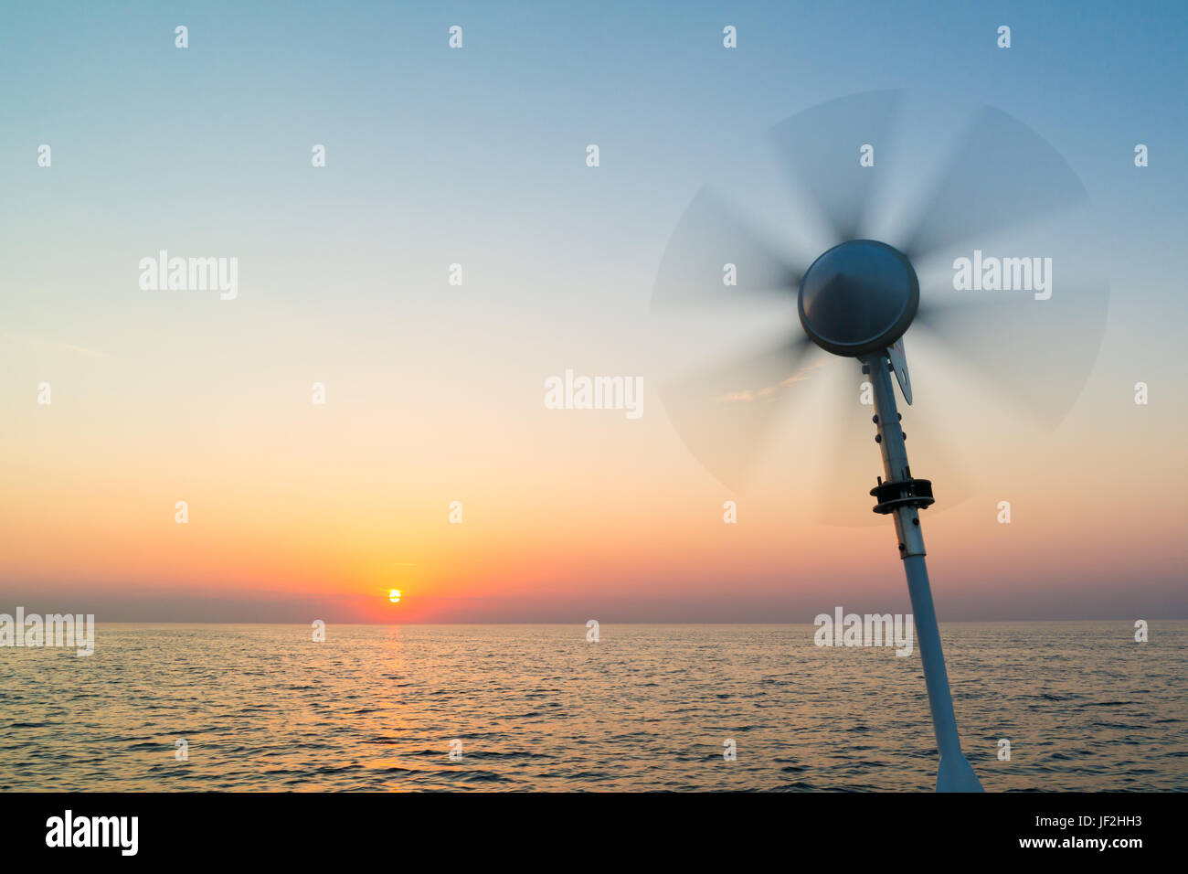 Éolienne Marine sur bateau à voile avec lames tournant à l'aide de l'énergie éolienne pour charger les batteries à bord de mer du Nord au coucher du soleil, Pays-Bas Banque D'Images