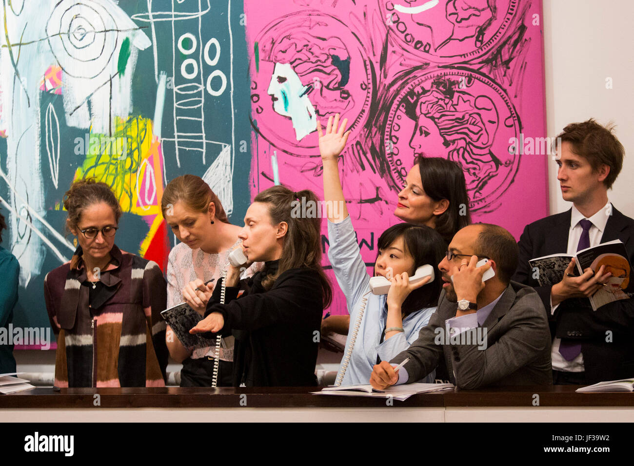 Londres, Royaume-Uni. 28 juin 2017. Sotheby's personnel téléphone les offres des cliients en face de l'Andy Warhol et Jean-Michel Basquiat collaboration nouvelle flamme, 1985, qui a vendu pour 2 408 750 GBP. Soirée d'art contemporain de Sotheby's Vente aux enchères a lieu à leurs nouveaux locaux de Bond Street. Banque D'Images