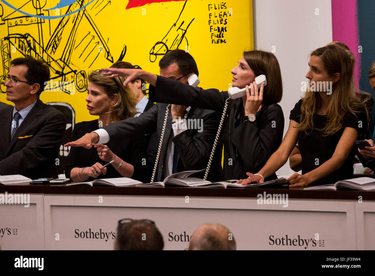 Londres, Royaume-Uni. 28 juin 2017. Sotheby's personnel téléphone les offres des cliients en face d'Andy Warhol et Jean-Michel Basquiat's, Sweet piquant, 1984-85, qui a vendu pour 4 433 750 GBP. Soirée d'art contemporain de Sotheby's Vente aux enchères a lieu à leurs nouveaux locaux de Bond Street. Banque D'Images