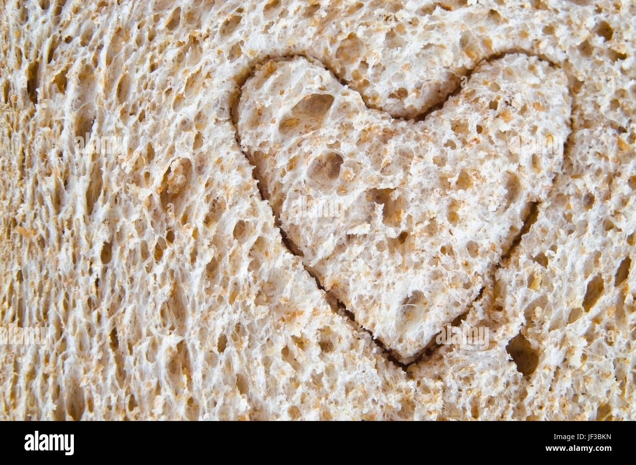 Gros plan (macro) de pain complet avec une forme de coeur coupé en elle, pour illustrer l'amour ou un coeur en santé diète. Banque D'Images