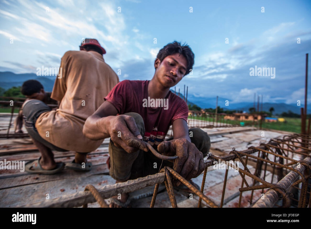 Jeune homme travaillant avec des barres d'armature lors de la construction d'une maison dans le district de Nuwakot, Népal Banque D'Images