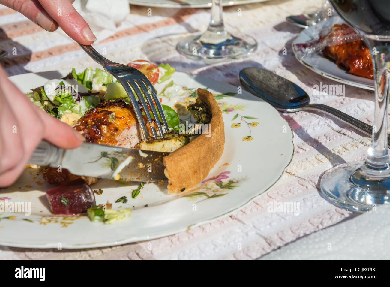 Gros plan de l'alimentation d'été mangées - plein air - sur une assiette. Fourchette et couteau coupe dans une quiche. Les repas à l'extérieur. Le Shropshire, Angleterre Banque D'Images