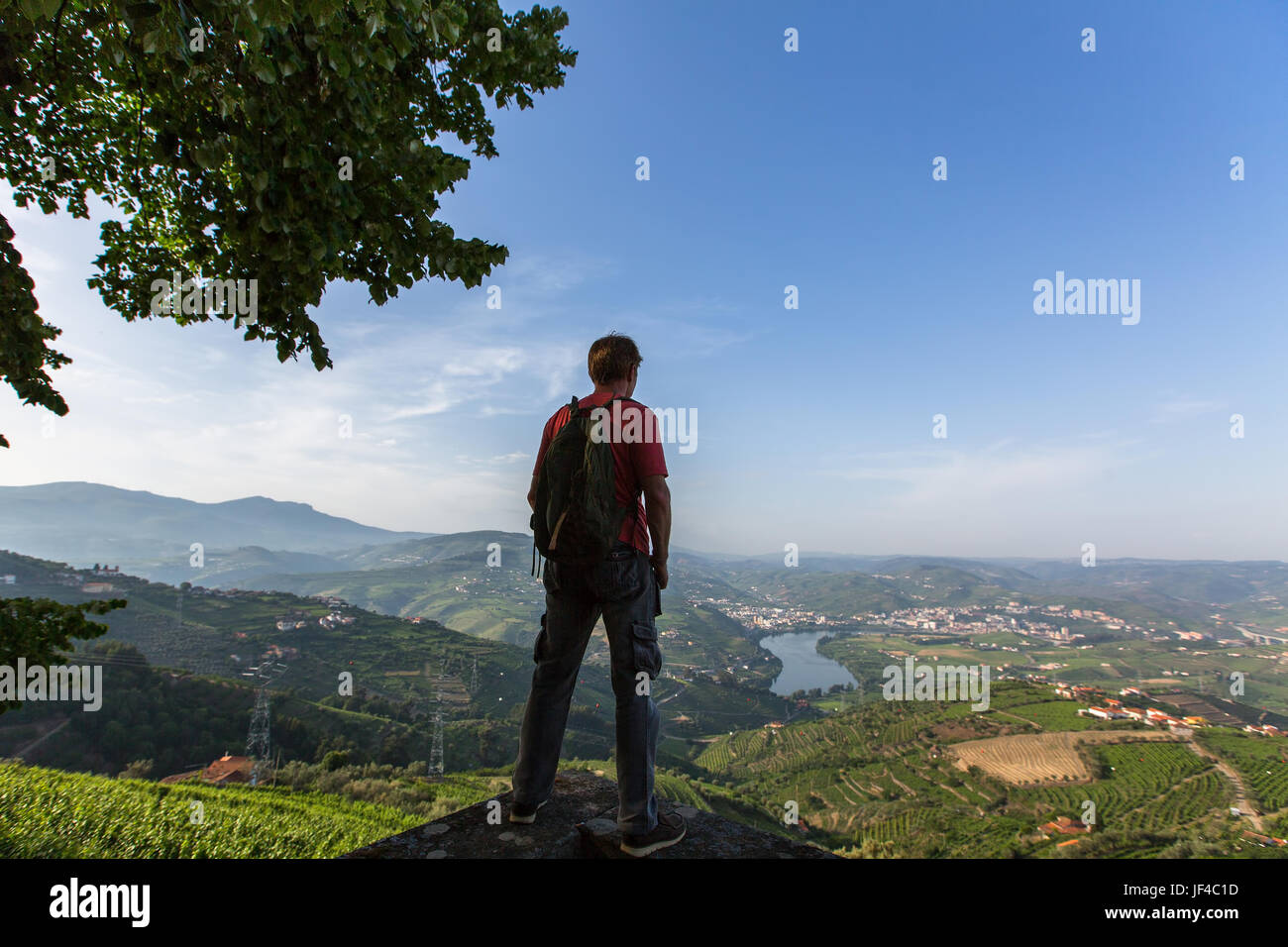 Homme hiker with backpack debout au sommet d'une montagne et profiter de la vue sur la vallée du Douro, Portugal. Banque D'Images
