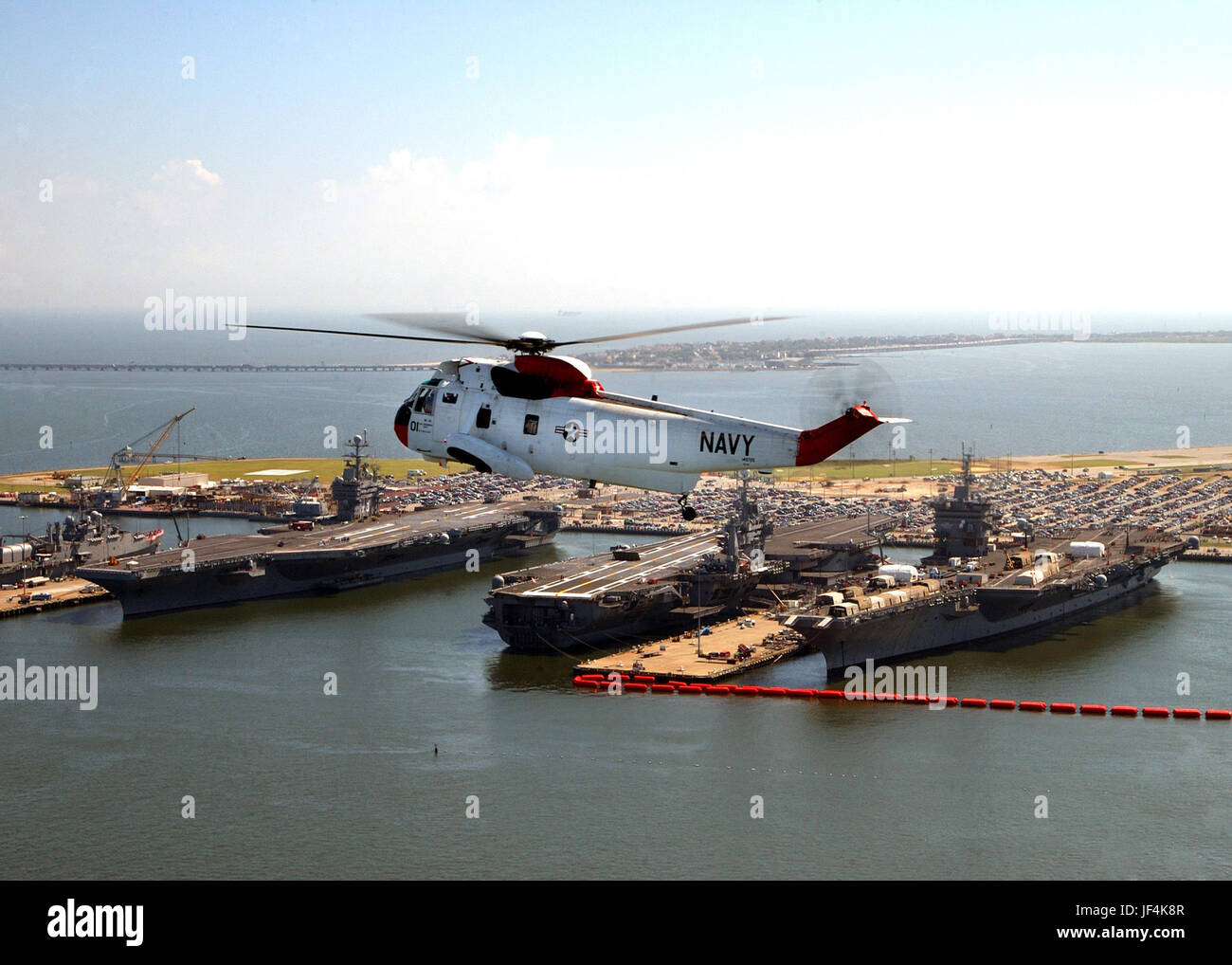 040827-N-4459K-002 un UH-3H hélicoptère Sea King vole près de trois porte-avions amarré à la Naval Station Norfolk, Va., le 27 août 2004. Les transporteurs sont (de gauche à droite), USS Harry S. Truman (CVN 75), USS George Washington (CVN 73) et l'USS Enterprise (CVN 65). L'hélicoptère est affecté à l'unité de recherche et sauvetage au Naval Air Station Oceana, Va. DoD photo de Maître de 1re classe Anthony M. Koch, Marine américaine. (Publié) Banque D'Images