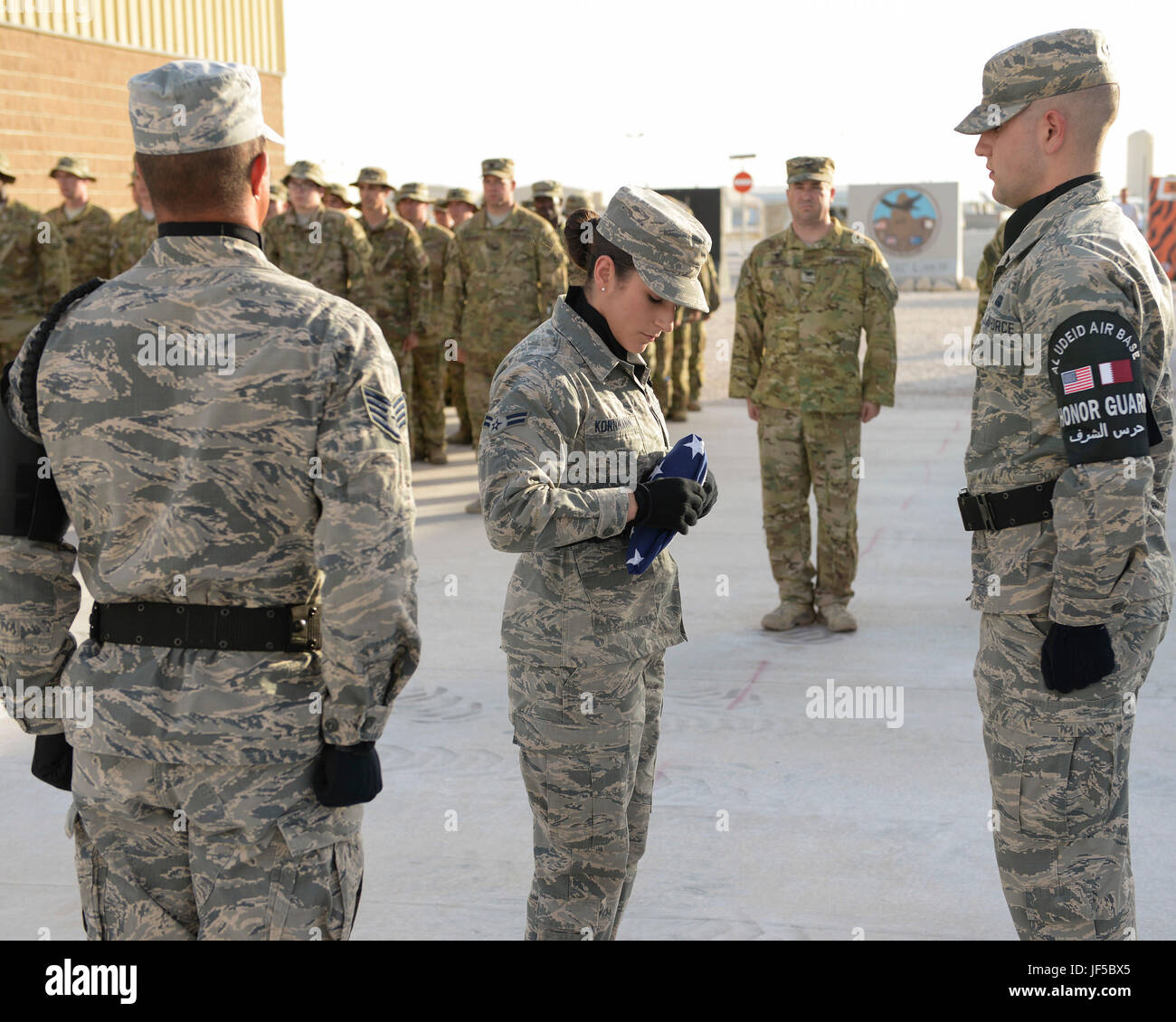 Les aviateurs de l'US Air Force 1re classe Jessica Kornmann, 379e Escadre expéditionnaire de la garde d'honneur, plie le drapeau américain tandis que d'autres membres de la garde d'honneur ainsi que des membres d'Al Udeid Air Base stand dans salut en Al Udeid Air Base, au Qatar, le 29 mai 2017. Le drapeau la retraite était partie d'une journée de réflexion tenue cérémonie commémorative en l'honneur de ceux qui sont morts en service militaire. (U.S. Air Force photo de Tech. Le Sgt. Bradly A. Schneider/libérés) Banque D'Images