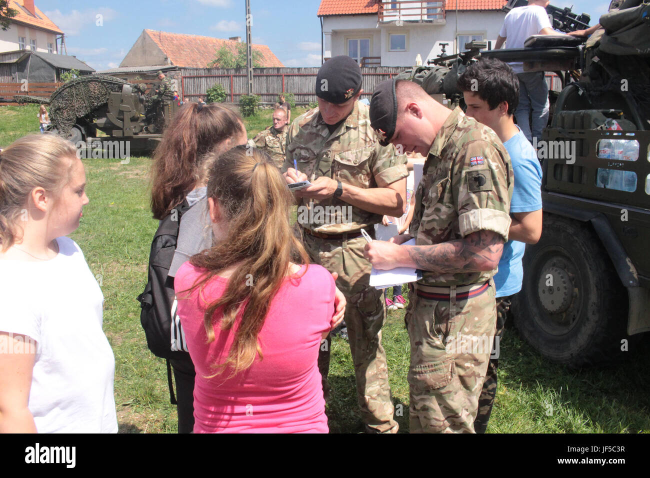 Pologne Groupe de combat des soldats britanniques signer des autographes pour les étudiants d'une école locale de Wydminy, la Pologne au cours de l'OTAN de l'école Jours de l'événement le 30 mai . Le groupement tactique est en Pologne dans le cadre de l'OTAN et de la présence accrue de l'avant les États-Unis, le Royaume-Uni et les soldats roumains de l'unité multinationale ont été très actif avec les communautés voisines tout comme un moyen de rendre les citoyens conscients de leur présence et d'en apprendre davantage sur la mission du groupe de combat. (U.S. Photo de l'armée par le Sgt. Jimmy Golden /libéré) Banque D'Images