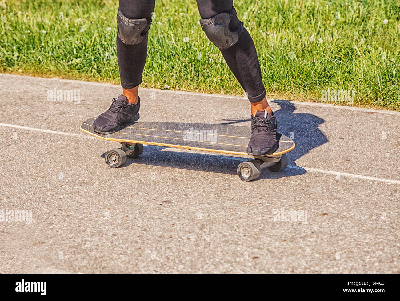 Jeune femme la planche à roulettes dans le parc aux beaux jours d'été gros plan des jambes. Banque D'Images