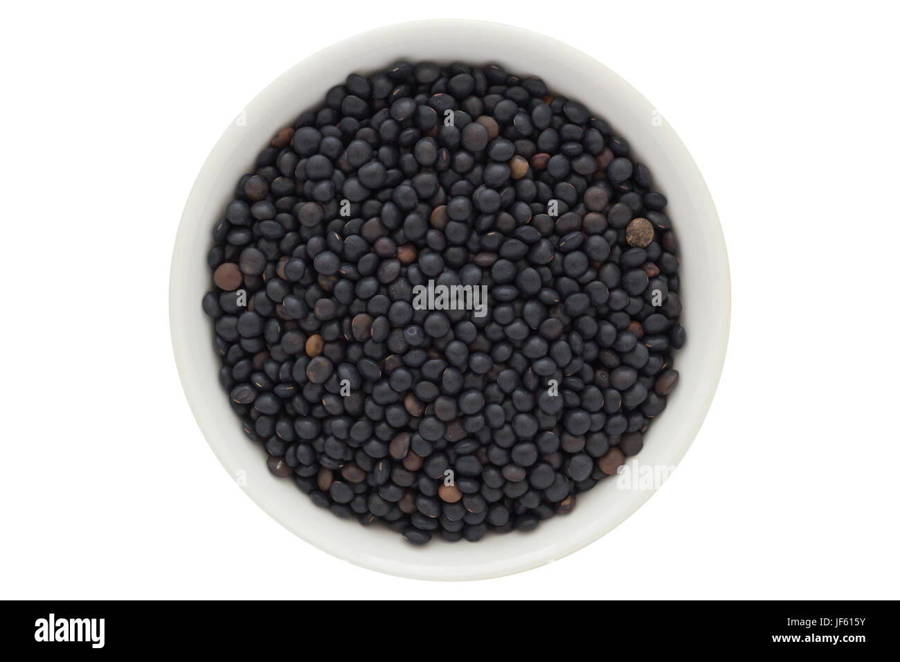 Graines de lentille Beluga dans bol blanc, isolé sur fond blanc Banque D'Images