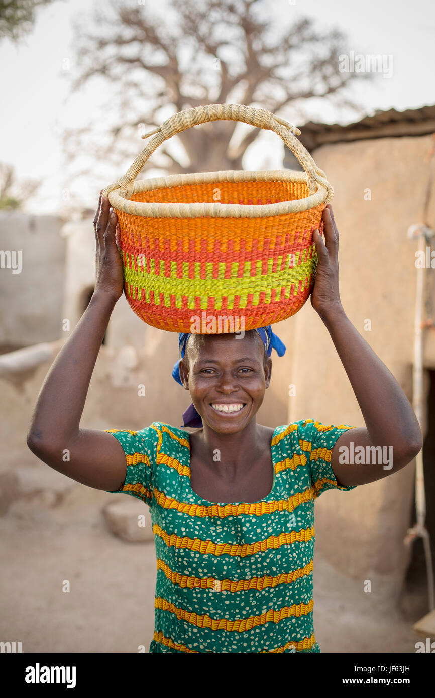 Une femme est titulaire d'un panier de paille traditionnel dans la région du nord-est, au Ghana. Banque D'Images