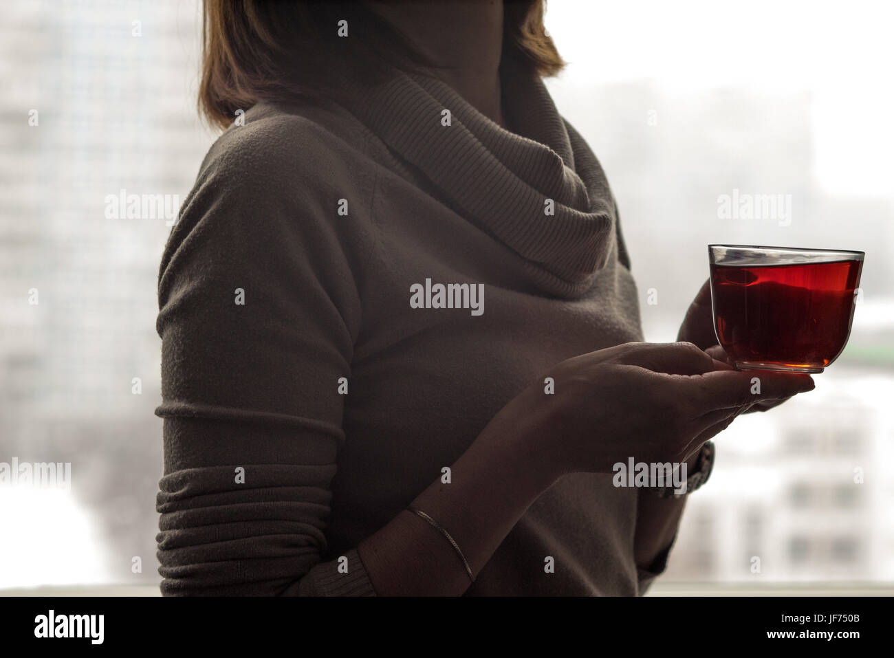 Femme près de la fenêtre avec tasse de thé Banque D'Images