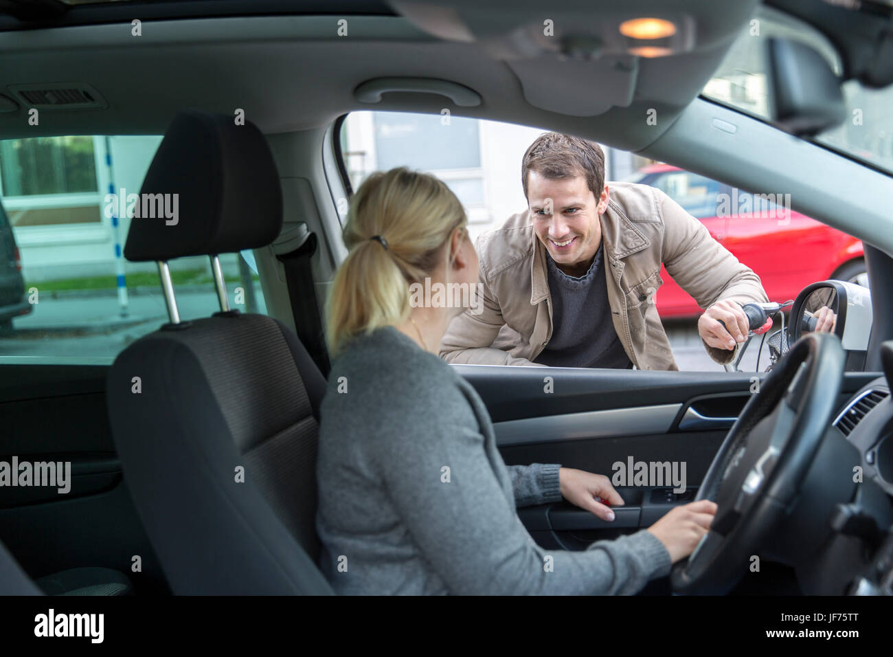 Parler à l'homme femme alors qu'elle est le moteur de voiture Banque D'Images