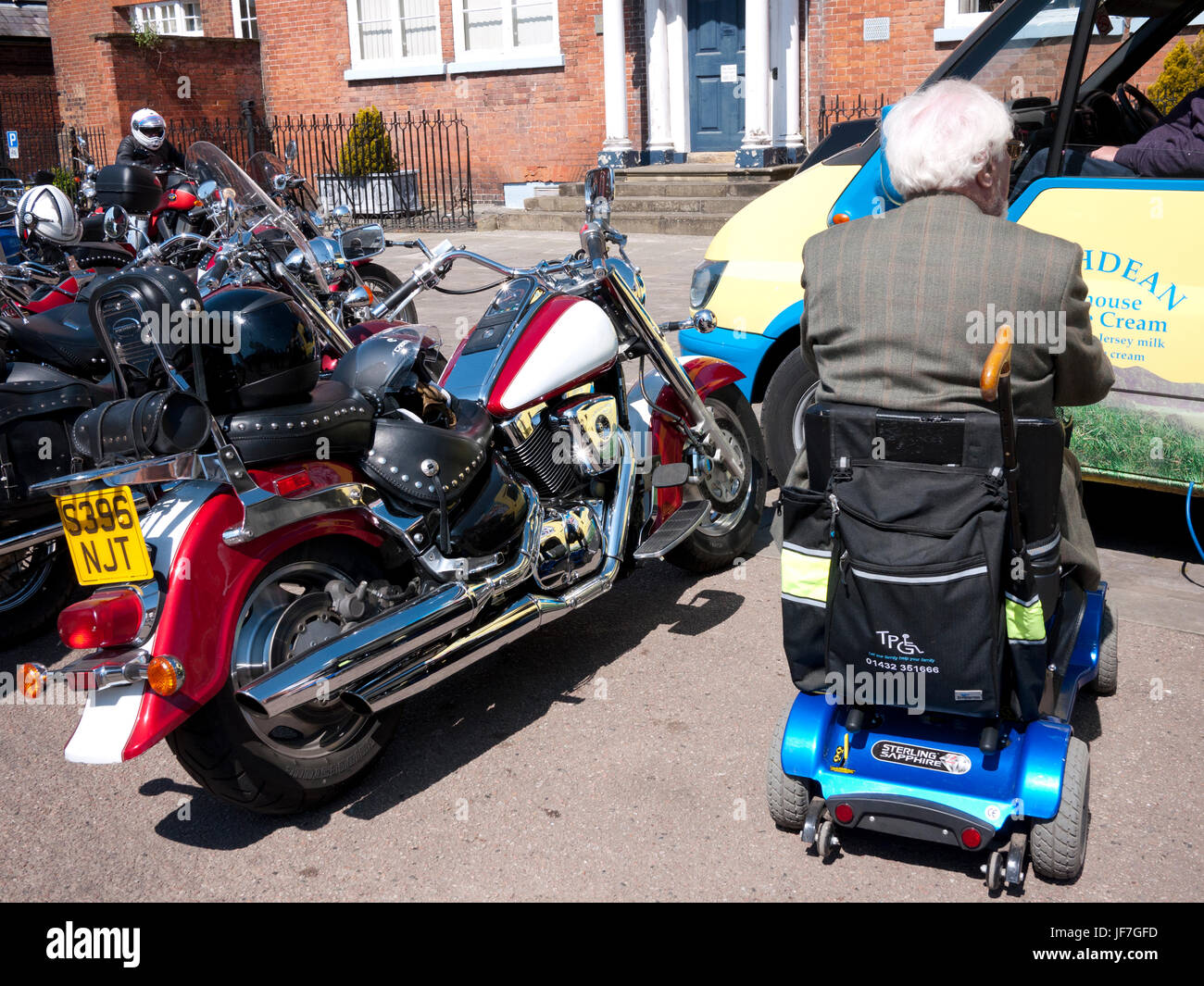 Pensionné handicapé sur la mobilité scooter garé à côté de grosse moto en attente d'être servis à la crème glacée van, Ludlow, Royaume-Uni. Banque D'Images