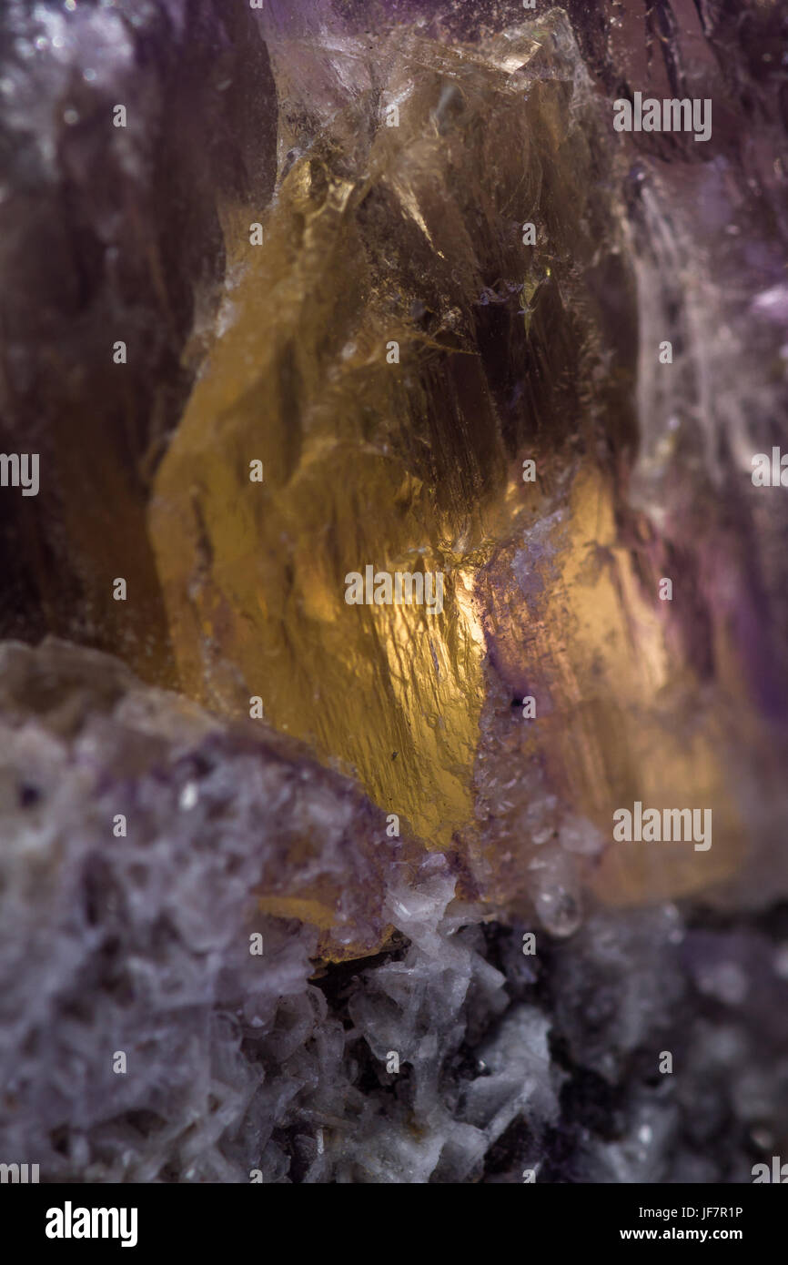 Gros plan d'une fluorite violet pierre avec un patch d'une croissance de cristaux d'or avec elle Banque D'Images