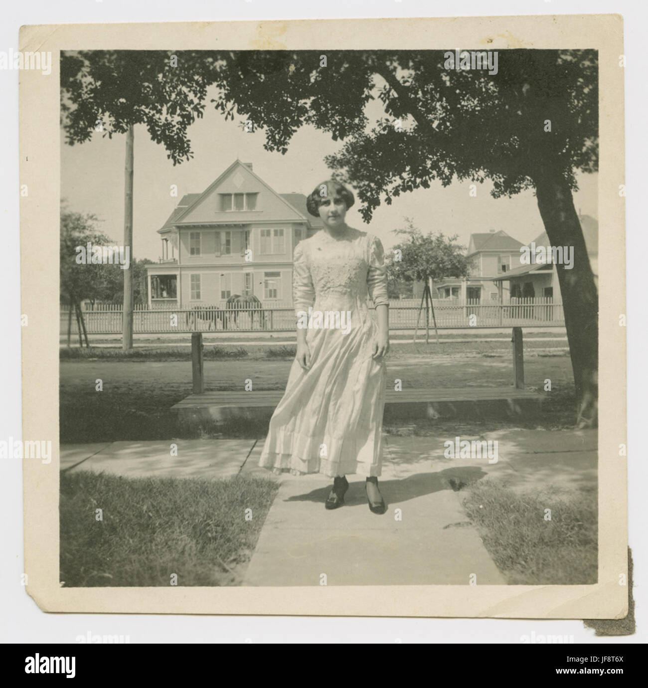 Une femme élégante portant une robe longueur cheville se promène dans les rues de Houston Heights, capturée dans cette photographie vintage des années 1920. Banque D'Images