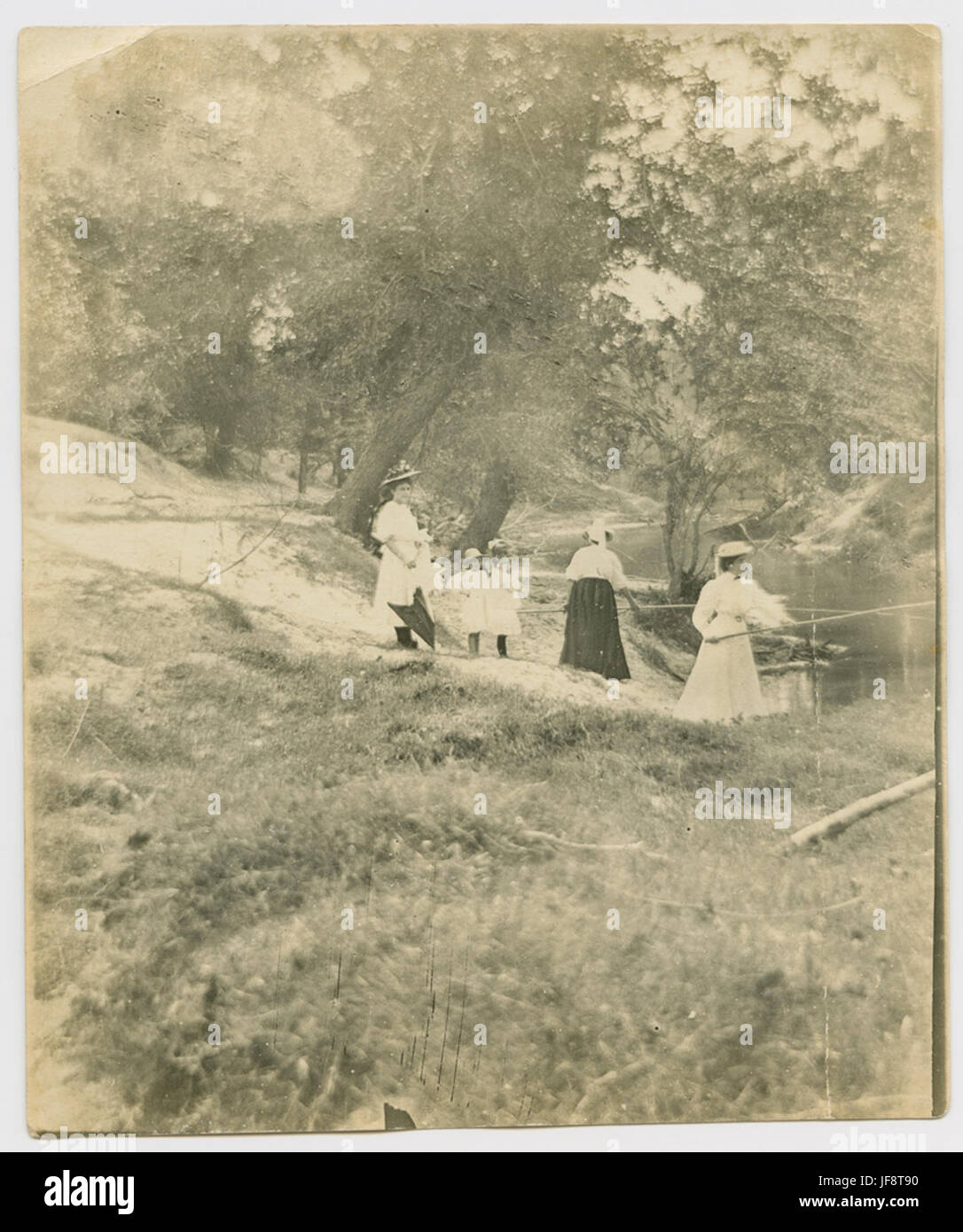 Une photographie historique de femmes et de filles debout le long de la rive de Houston Bayou, Texas, capturant un moment dans l'histoire culturelle et sociale de la ville. Banque D'Images