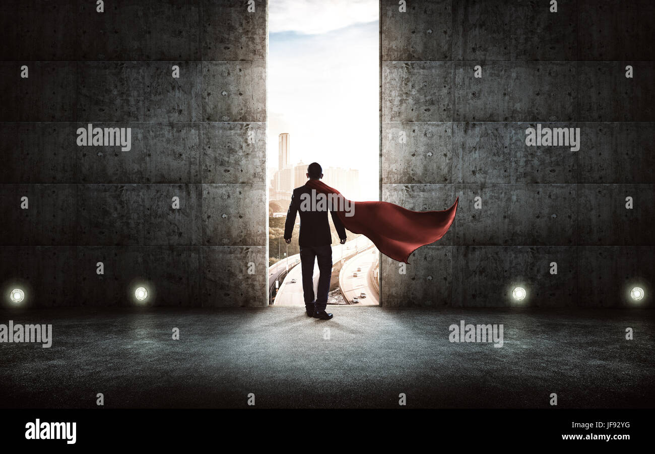 Businessman en costume et cape position à l'encontre d'escalier mur de béton avec des portes