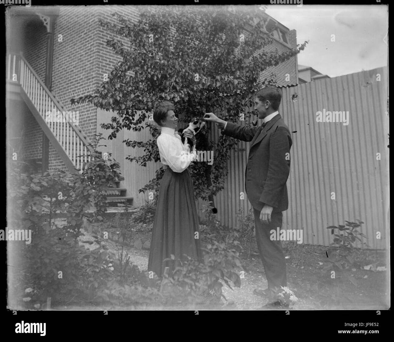 Une photographie historique de Gundagai montrant une femme tenant un chat, debout à côté d'un homme, capturant un moment de la vie quotidienne dans le passé. Banque D'Images