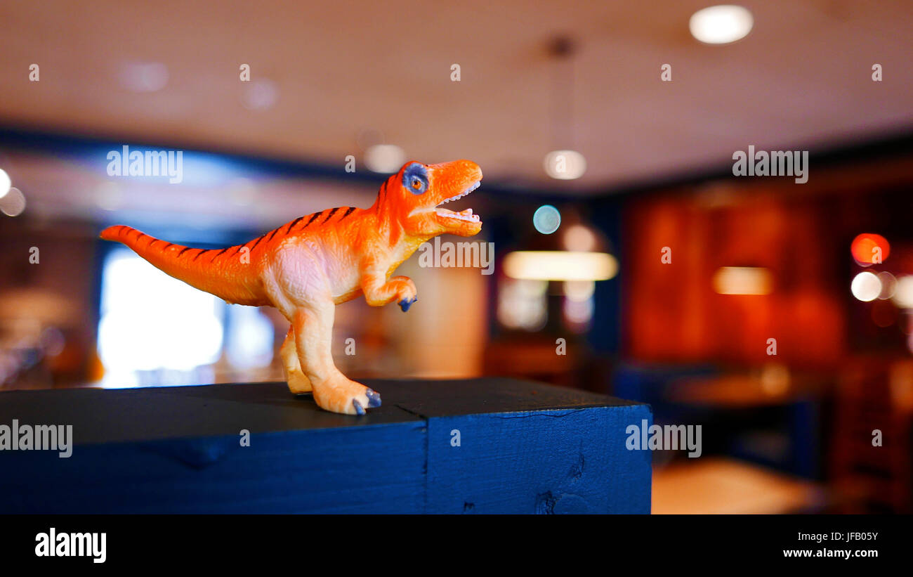 Petit modèle en plastique orange d'un Tyrannosaurus Rex se tenait sur étagère dans un intérieur éclairé Banque D'Images