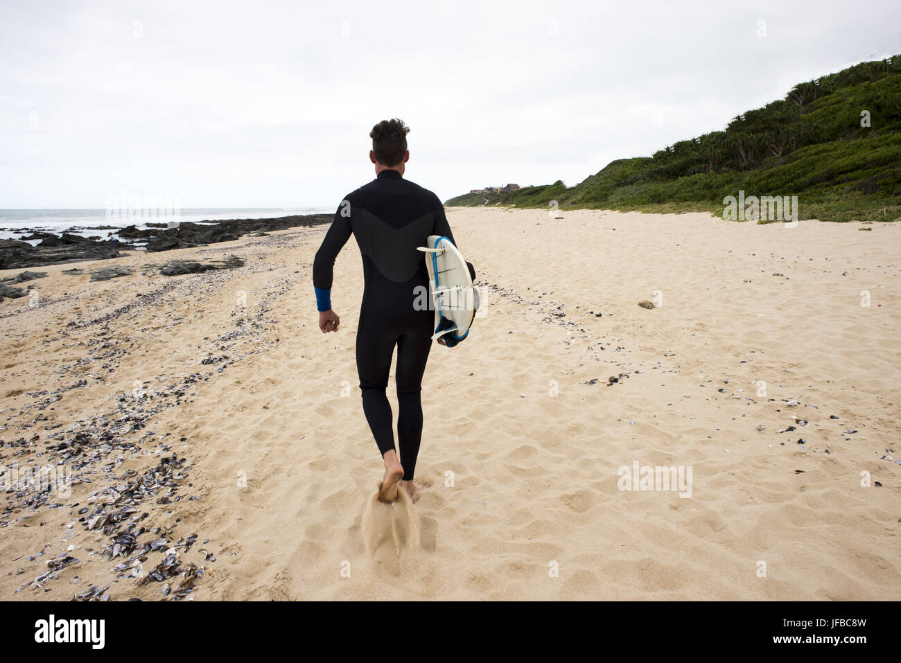 Surfer promenades le long beach Banque D'Images