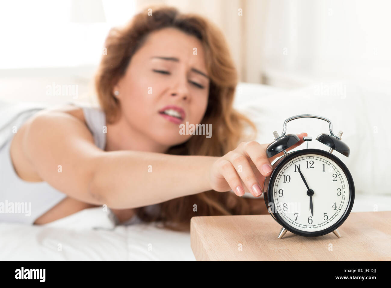 Jeune femme endormie essayant d'éteindre le réveil. Se réveiller tôt le  matin Photo Stock - Alamy