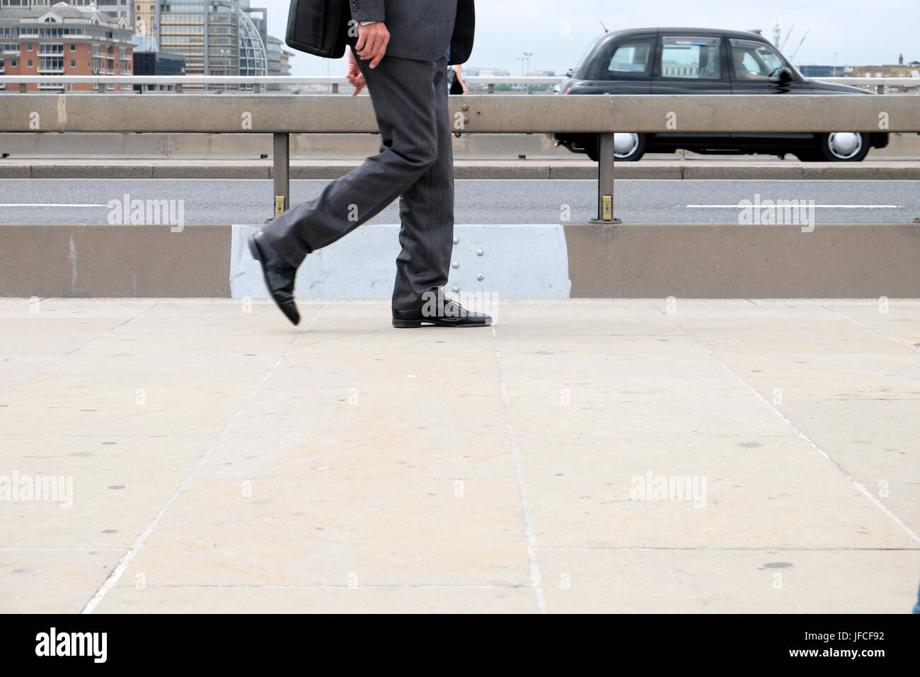 Businessman walking de travailler le long côté de la chaussée en béton anti-terroriste sur le pont de Londres après 2017 UK agression au couteau KATHY DE WITT Banque D'Images