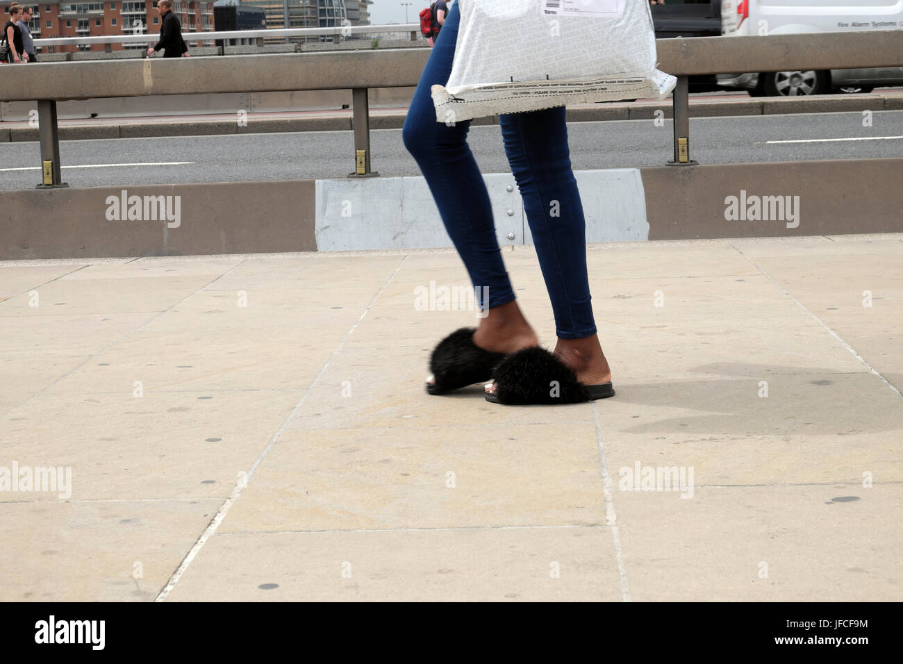 Femme avec furry slip-on marcher le long de la chaussure à côté de lutte anti-terroriste barrière de béton sur le pont de Londres après 2017 UK agression au couteau KATHY DE WITT Banque D'Images
