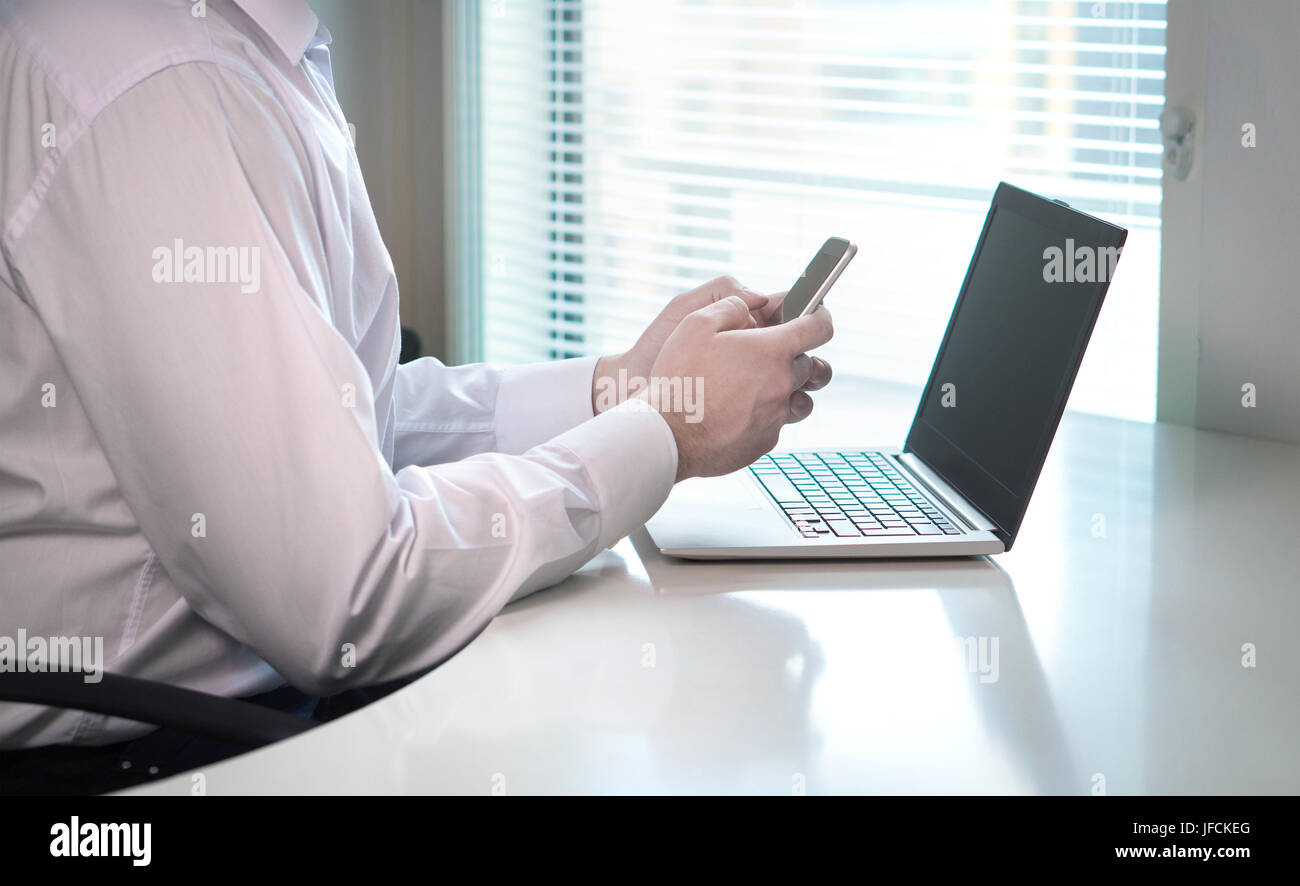 Businessman typing et écrit avec le smartphone de bureau à la maison ou les collègues de travail. Man texting ou répondre à votre e-mail de votre téléphone mobile. Restant en retard à Banque D'Images