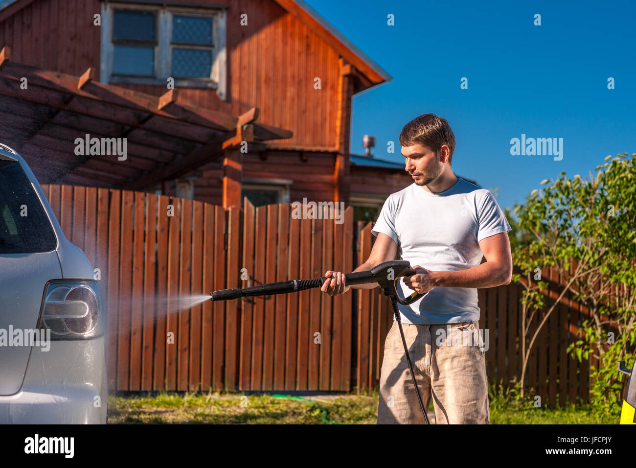 Man washing car in front of house Banque D'Images