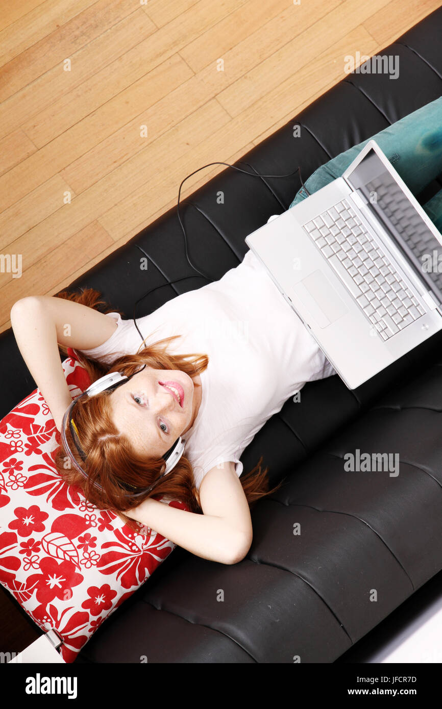 Jeune fille rousse surf sur le canapé Banque D'Images