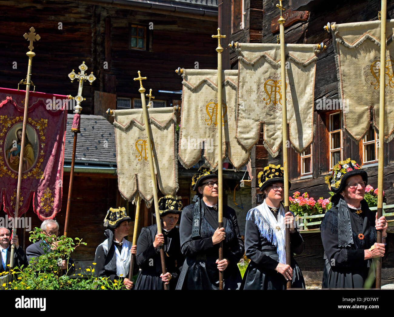 Femme en costumes traditionnels avec des bannières, drapeaux, église procession du Corpus Christi, Blatten, Lötschental, Valais, Suisse Banque D'Images