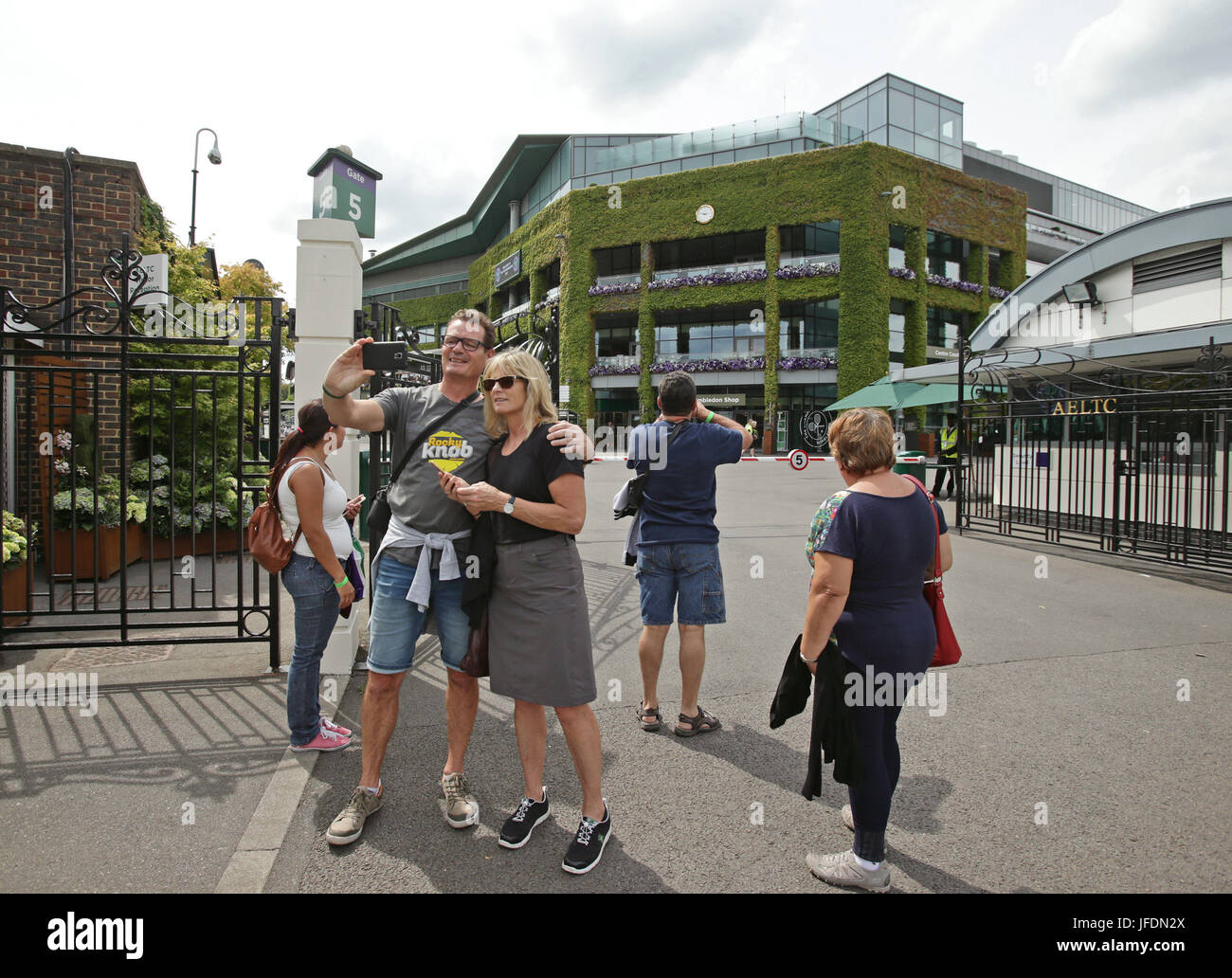Passants de prendre un avec le All England selfies Tennis Club en arrière-plan , l'avant du tournoi de tennis de Wimbledon, dans le sud-ouest de Londres. Banque D'Images