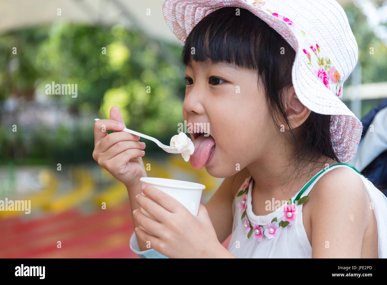 Chinois asiatique little girl eating ice cream au parc extérieur Banque D'Images