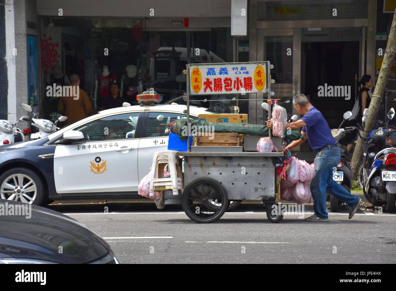 Un stand alimentaire personne pousse son panier au-delà d'un poste de police près de l'hôpital Mackay. Taipei, Taiwan. Banque D'Images