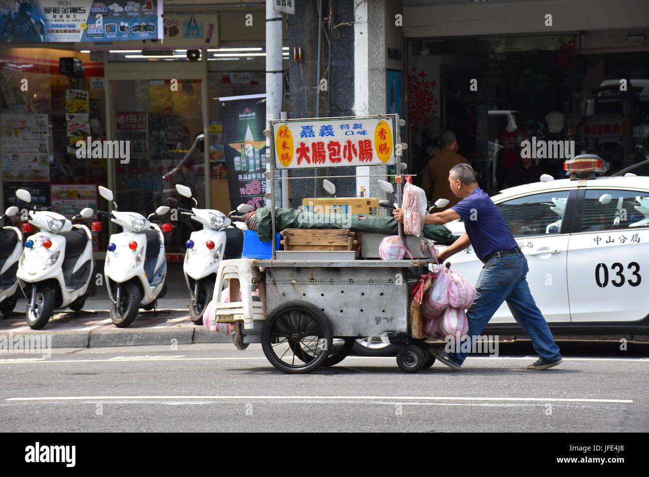 Un stand alimentaire personne pousse son panier au-delà d'un poste de police près de l'hôpital Mackay. Taipei, Taiwan. Banque D'Images