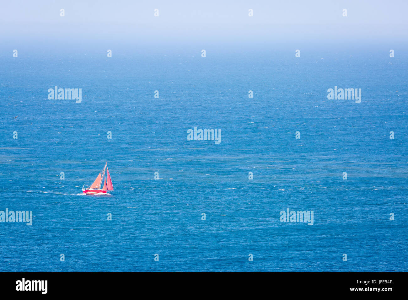 Yacht à voile (rouge) avec orange-brun, voile voiles au vent latéral, plus de gîte dans la mer au large de l'île de Skomer. Banque D'Images