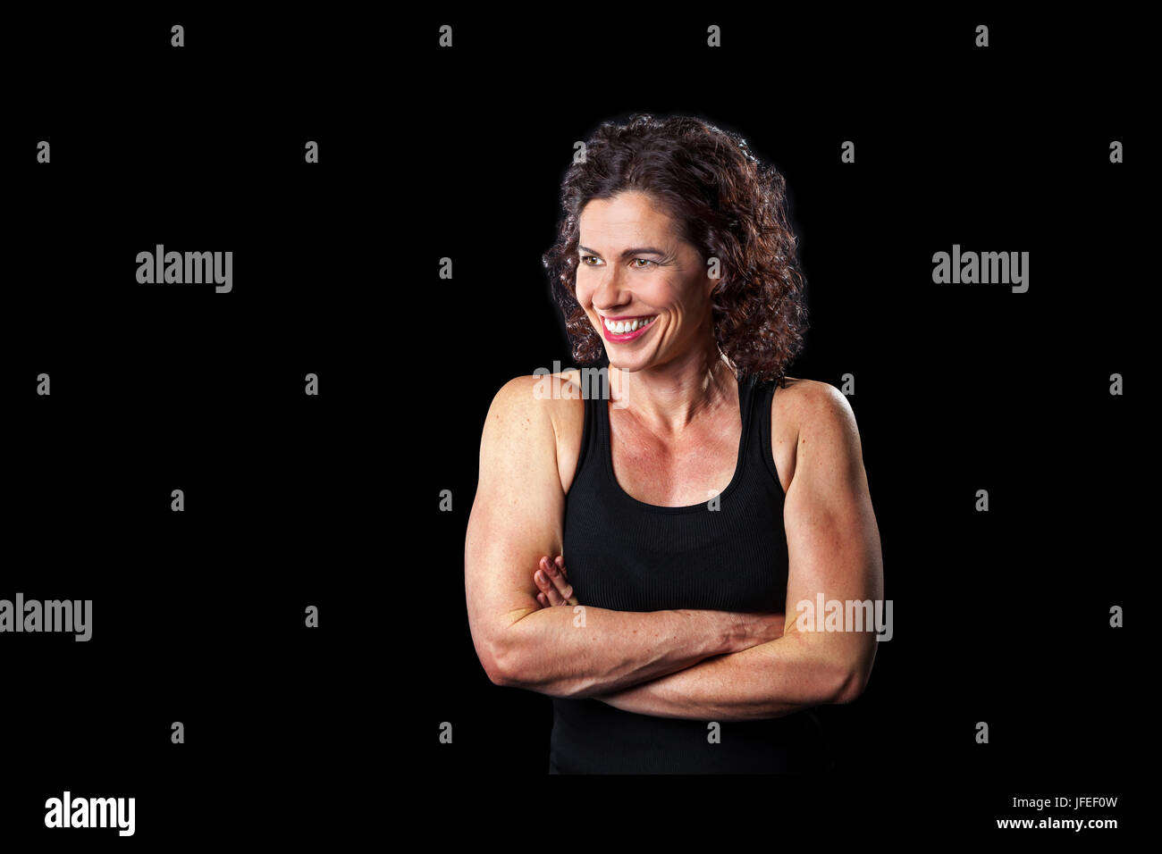 Portrait of a woman smiling musculaire et à la recherche sur un côté. Beaucoup d'espace et de copie trajet autour de la femme. Fond noir, allumé. Banque D'Images