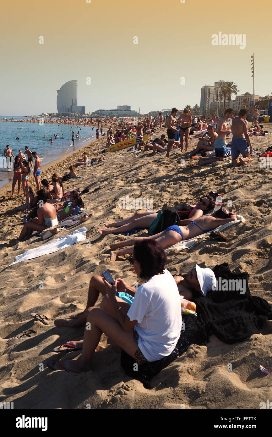 Des foules de gens en train de bronzer sur la plage de la Barceloneta, l'Hôtel W à l'arrière-plan, Barcelone, Espagne Europe Banque D'Images