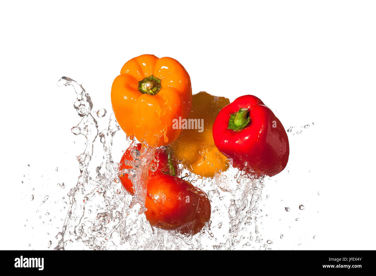 Orange, jaune et rouge avec tomates poivrons éclaboussant par l'eau. Banque D'Images