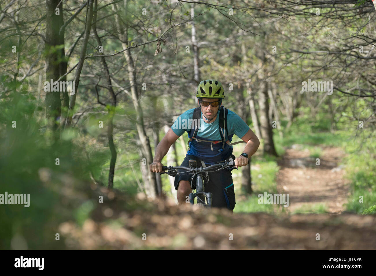 Biker équitation randonnée sur chemin de terre en forêt d'arbres Banque D'Images